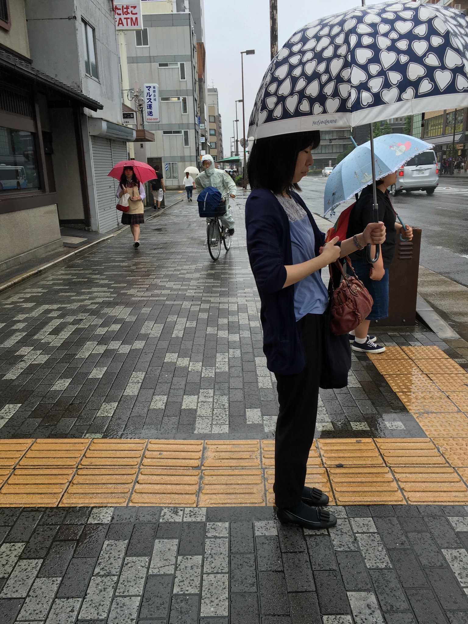 With rain comes umbrellas of many sizes and colours. They make negotiating the streets more challenging, especially with the bikes still weaving in-between the pedestrians. When they have umbrellas as well, such as in the image above, the space becomes even more limited.
